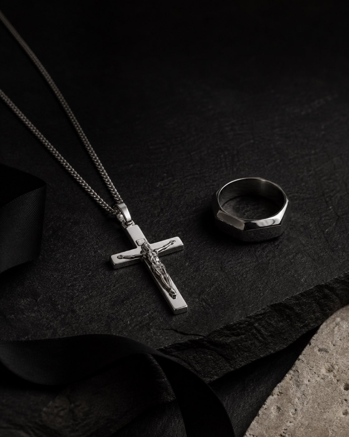 Polished silver crucifix pendant on black stone