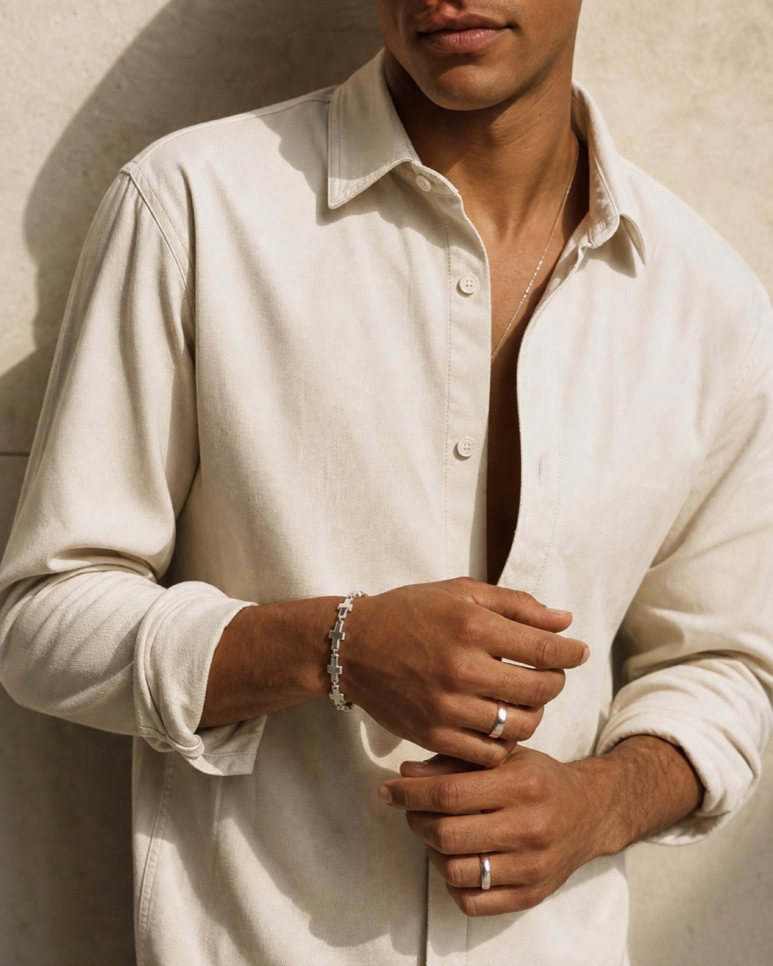Man wearing a silver cross-link bracelet and rings