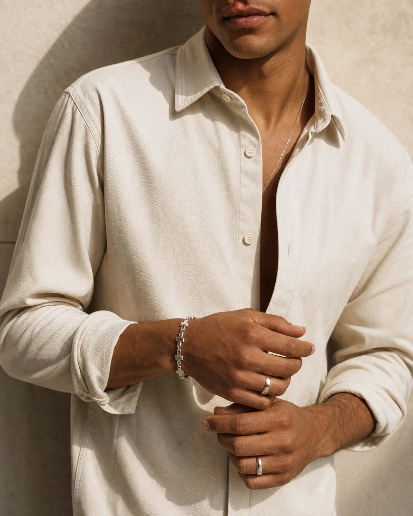 Man wearing a silver cross-link bracelet and rings
