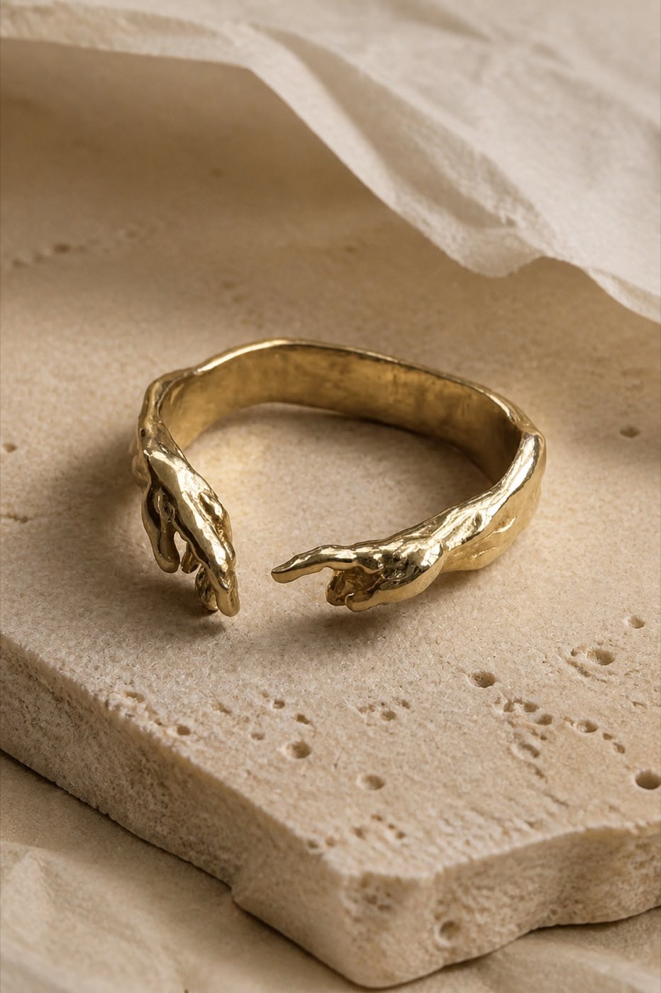 Gold Creation of Adam ring styled on warm limestone