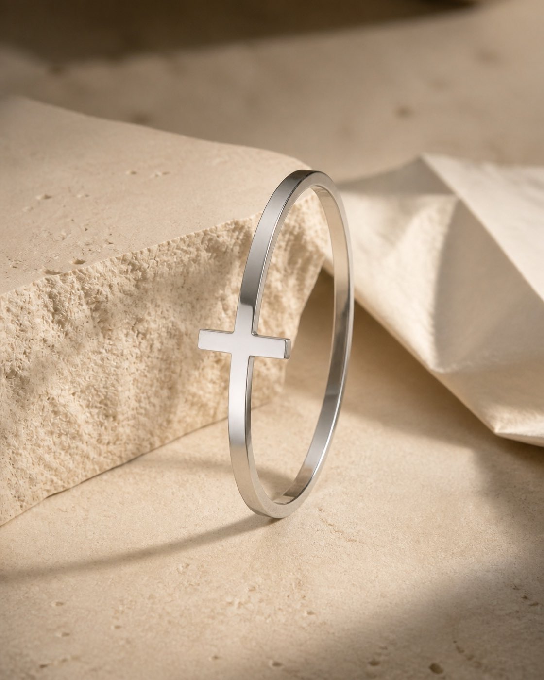Silver Tethered Cross bracelet styled on warm limestone
